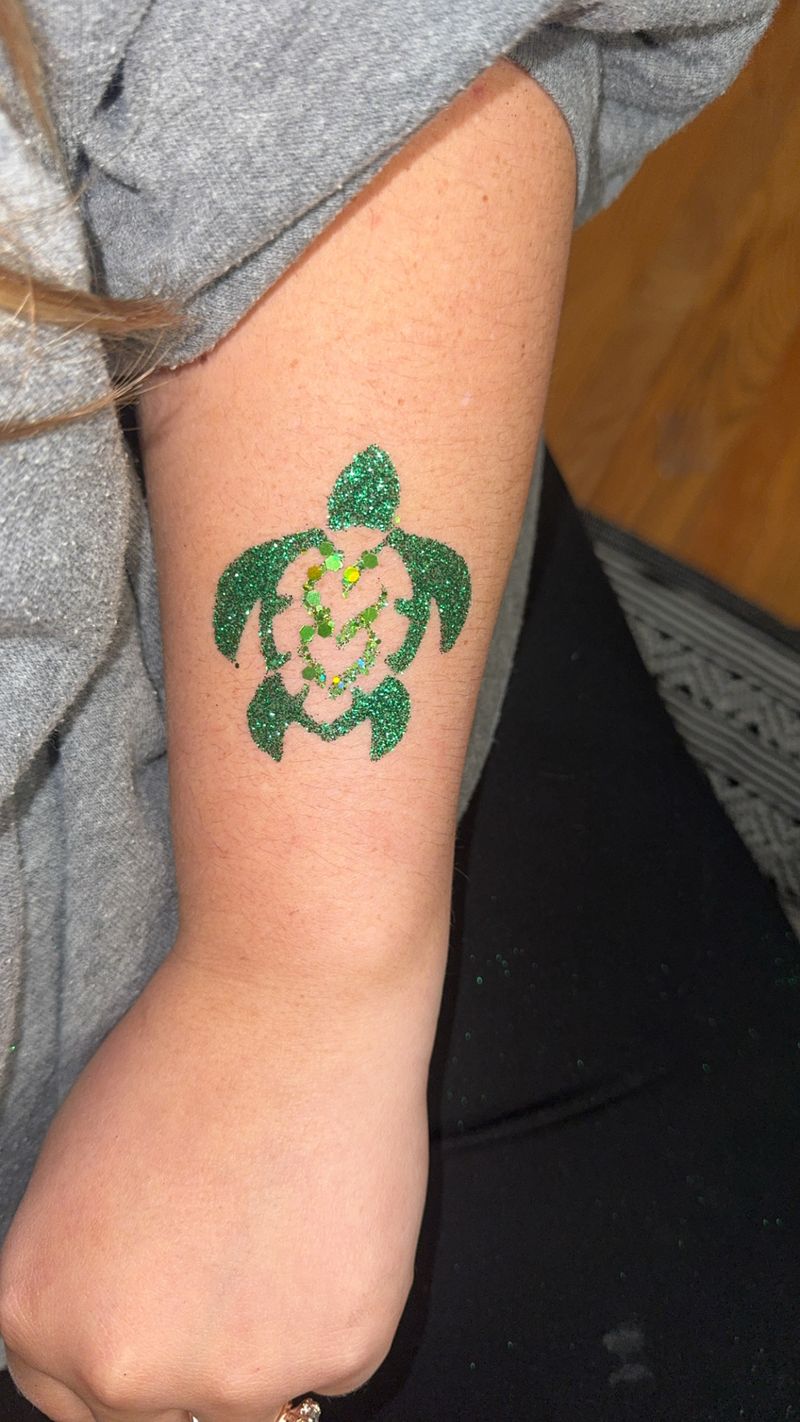 Green sea turtle glitter tattoo design on an arm at a Texas party