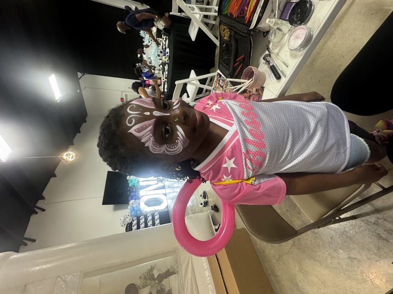 Princess butterfly face painting with pink balloon wings at a Texas birthday party