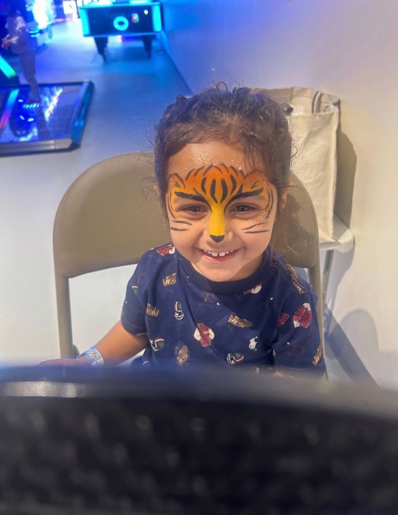 Tiger face painting for a boy at an arcade birthday party in Texas